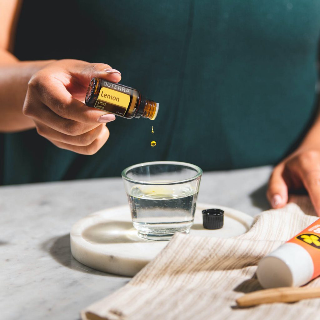 lady putting drops of essential oils into a glass