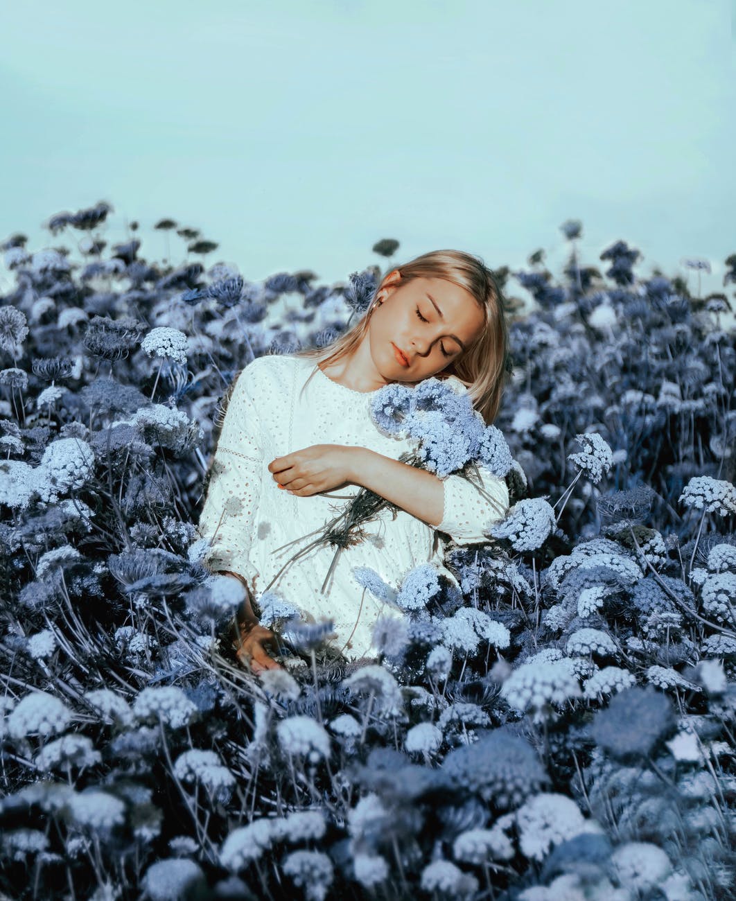 serene female holding bunch of flowers in meadow