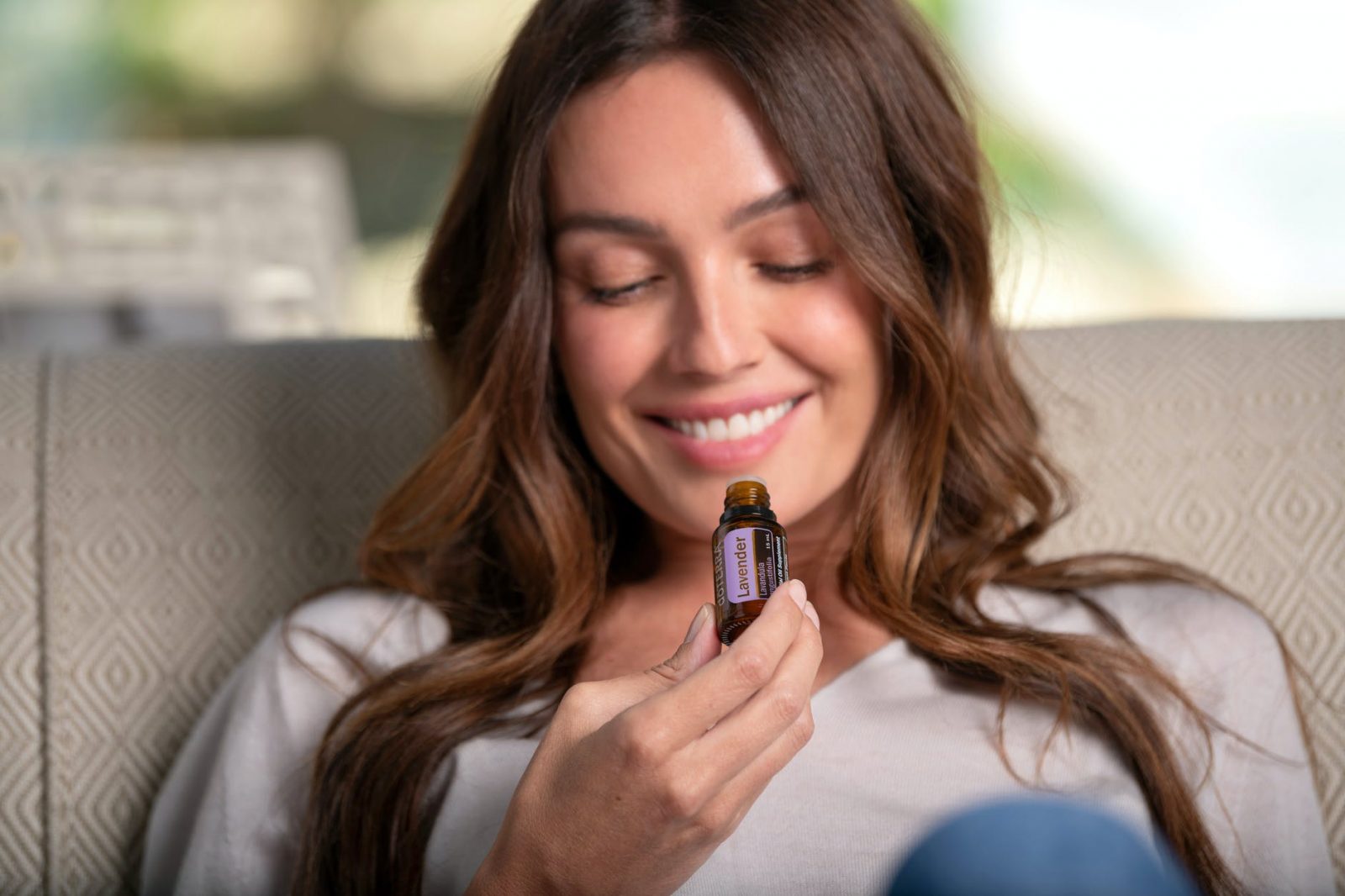 woman smiling holding a bottle of essential oil